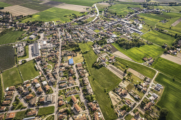 Captivating aerial perspective of a quaint village nestled amidst the lush, green Po Valley farmlands in Italy