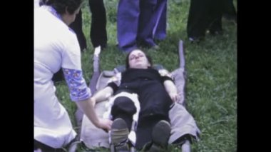 Bellinzona, İtalya 1975: 1970 'lerden kalma yaralı ve kurtarma ekiplerinin bulunduğu çoklu sedyelerin yer aldığı bir sahneyi gösteren klasik video klibi