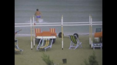 Fano, İtalya Temmuz 1975: 1970 'lerde yağmurun altında kumsalda eğlenen erkeklerin yer aldığı bu büyüleyici video kliple zamanda geri gidin.