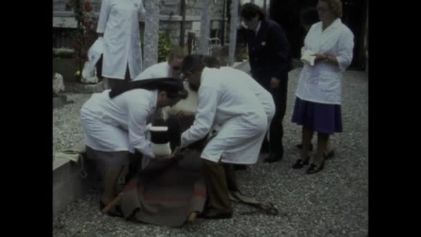 1975年5月イタリア ベリンゾナ州 1970年代に屋外でストレッチャーを装着するなど 負傷した男性に提供された救助と医療を紹介するヴィンテージビデオクリップで過去に足を踏み入れてください — ストック動画