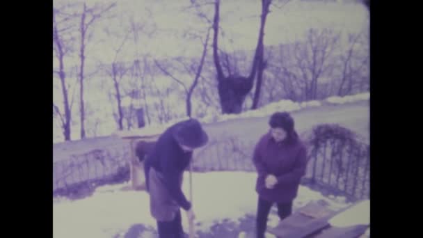1975年 昭和50年 5月イタリア ローマ1970年代の雪の冬にタイムスリップし 自宅の車道から雪を晴らす老夫婦の回復力を目の当たりにする — ストック動画