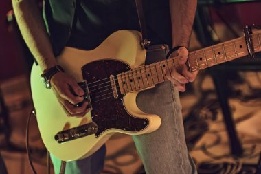Yakın çekim, hassas ve tutkulu bir şekilde gitar çalan bir elin karmaşık hareketlerini yakalıyor..