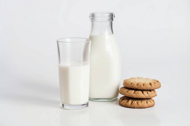 Beyaz arka planda bisküviler ve bir bardak sütün yer aldığı davetkar bir sabah sahnesi, kahvaltı kavramları için mükemmel..