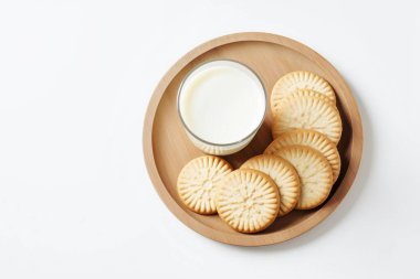 Beyaz arka planda bisküviler ve bir bardak sütün yer aldığı davetkar bir sabah sahnesi, kahvaltı kavramları için mükemmel..