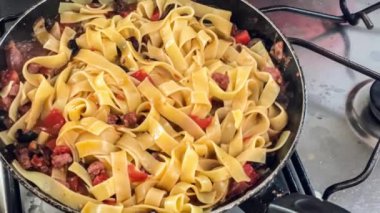 Ev mutfağında Akdeniz usulü makarna pişirirken çekilmiş yakın çekim görüntüler..