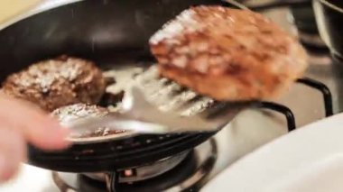 Ev mutfağında bir tavada hamburger hazırlama görüntüsü..