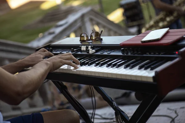 Close-up of a pianist\'s hands skillfully playing the keyboard during a live daylight performance.
