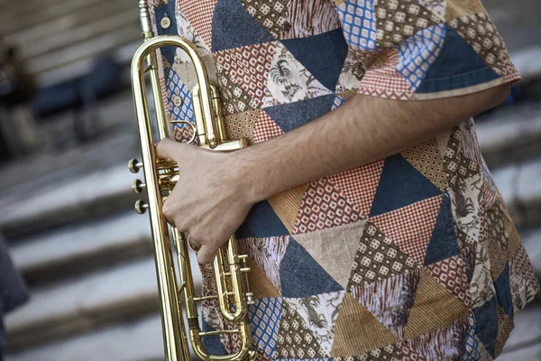 Close-up of a musician's hands playing the trumpet during a vibrant live performance in daylight.