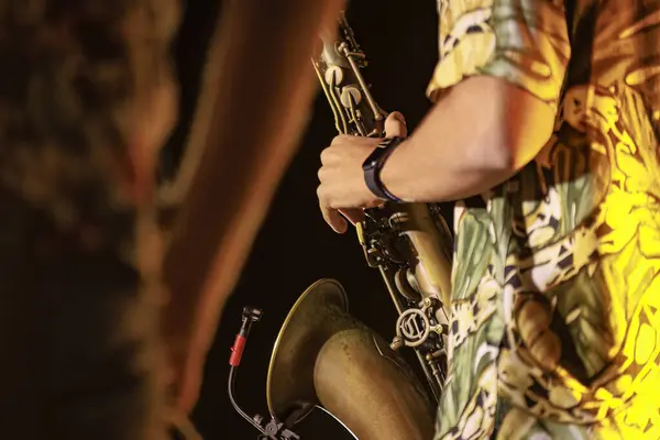 Close-up of a musician\'s hands playing the trumpet during a vibrant live performance at night