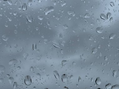 Penceredeki yağmur damlalarının yakın çekim dokusu.