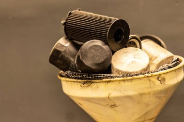 Bir atölyedeki eski, tükenmiş yağ filtrelerinin fotoğrafı otomotiv bakımındaki tehlikeli atık imhası sembolize ediliyor..