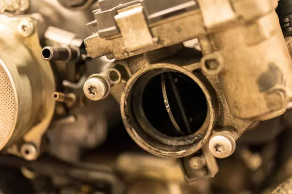 Araba motoru içindeki kirli bir gaz vanasının kumlu detaylarını yakalayan bir fotoğraf..