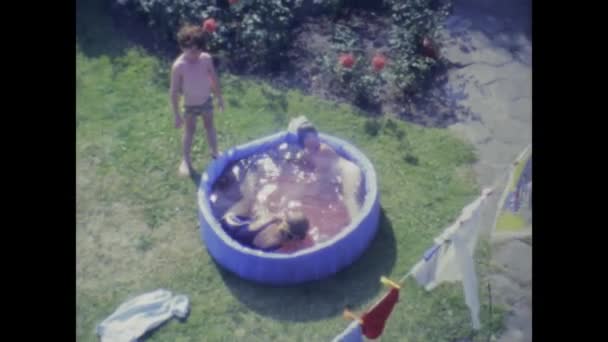 1975年6月 デンマーク コペンハーゲン 70年代に裏庭に膨脹可能なプールで爆発する子供たち — ストック動画