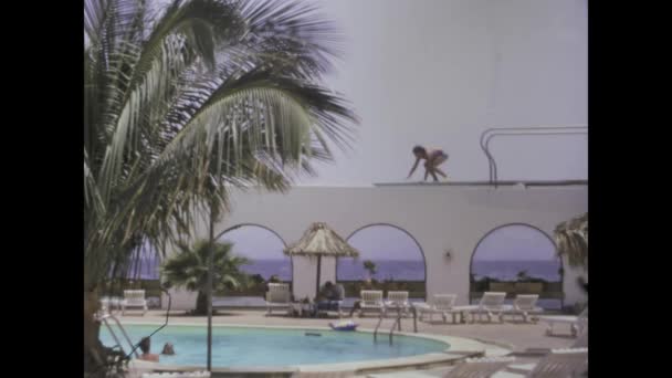 西班牙大加那利亚可能在1975年 一个孩子在跳水跳板上犹豫不决 克服了恐惧 最后在70年代跳进了游泳池 — 图库视频影像