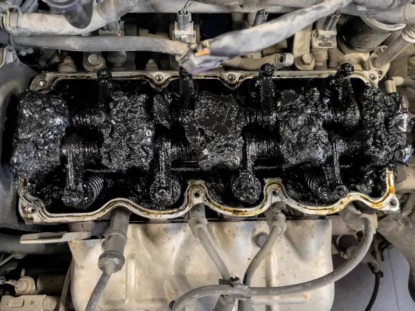 Car engine caked with residues and tar, a symbol of poor maintenance needing repair.