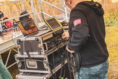 Milan, Italy 1 April 2024: A focused sound engineer at work, setting up equipment for a live performance, ensuring perfect audio quality. clipart