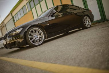 Roma, İtalya 18 Nisan 2024: Şehir caddesinde bir binanın önüne park edilmiş siyah bir araba.