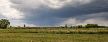 Sakin tarım arazilerinin üzerinde beliren kara fırtına bulutları dramatik bir kırsal manzara yaratıyor..