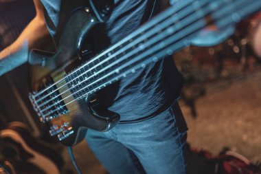 Bir açık hava gösterisi sırasında bas gitar çalan ellerin yakın çekimi.