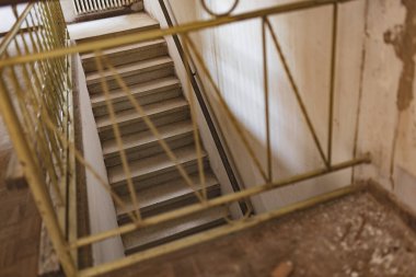 Eski bir evde eski bir korkuluğu olan, güneşli bir odaya çıkan bir iç merdiven manzarası..