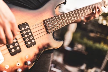 Bir açık hava gösterisi sırasında bas gitar çalan ellerin yakın çekimi.
