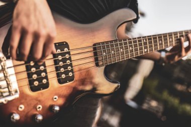 Bir açık hava gösterisi sırasında bas gitar çalan ellerin yakın çekimi.