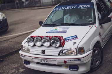 Gavello, İtalya 23 Haziran 2024: Bir Peugeot 106 ralli aracına yakın çekim ve sokak üzerine park edilmiş ekstra far ve sponsor çıkartmaları