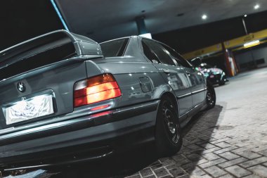 Adria, İtalya 30 Temmuz 2024: Gri BMW E36 Gri spoiler ve gece bir benzin istasyonuna park edilmiş tekerlekler