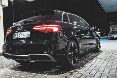 Adria, İtalya 30 Temmuz 2024: Parlak siyah Audi A3 modern tasarım ve şık jantlarla gece vakti bir benzin istasyonuna park edildi