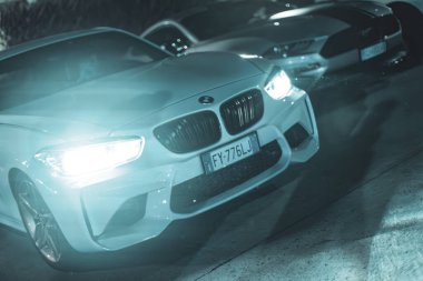 Adria, İtalya 30 Temmuz 2024: BMW Serisi 1 'in gece park edilmiş altın tekerlekleri, gösterişli parlak tasarımı ve modern otomotiv tarzı.
