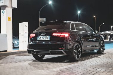 Adria, İtalya 30 Temmuz 2024: Parlak siyah Audi A3 modern tasarım ve şık jantlarla gece vakti bir benzin istasyonuna park edildi