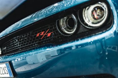 Adria, İtalya 30 Temmuz 2024: Mavi Dodge Challenger R / T rozetli bir Dodge 'un far ve ızgarasına yakın çekim.
