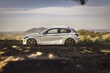 Milan, İtalya 28 Ağustos 2024: Arka planda tepe ve vadileri nefes kesen manzaralı bir BMW 1 Serisi F21.