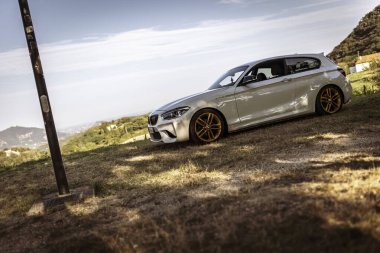 Milan, İtalya 28 Ağustos 2024: Doğayla çevrili bir BMW 1 serisi F21 ön cephelerinin düşük açılı yakın çekimi.