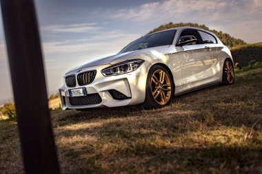 Milan, İtalya 28 Ağustos 2024: Pürüzsüz bir BMW 1 Serisi F21 altın jantlı kırsal bir yola park edilmiş, sürüş için hazır..