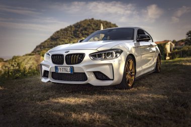 Milan, İtalya 28 Ağustos 2024: Pürüzsüz bir BMW 1 Serisi F21 altın jantlı kırsal bir yola park edilmiş, sürüş için hazır..
