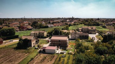 Geleneksel evler ve yeşil alanlar içeren Po Valley köyündeki bir yerleşim yerinin hava görüntüsü..