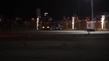 Villamarzana, İtalya 17 Eylül 2024: Sürüklenen bir araba pistte dumanlı bir sürüklenme manevrası yapıyor, gece bir motor sporu etkinliğinde yarışıyor