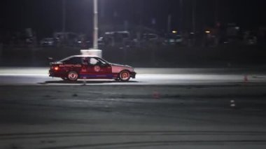 Villamarzana, İtalya 17 Eylül 2024: Sürüklenen bir araba pistte dumanlı bir sürüklenme manevrası yapıyor, gece bir motor sporu etkinliğinde yarışıyor