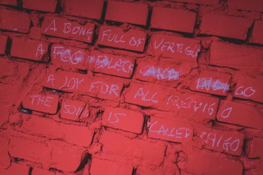 A hand chalking words onto a red brick wall with graffiti, adding a personal touch to the urban setting. clipart