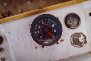 Paslı bir aracın torpido gözünde terk edilmiş ve unutulmuş bir sahneyi gösteren takometreye yakından bakın..