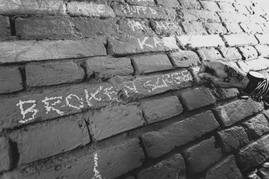 A tattooed hand writing on a textured brick wall with chalk, showcasing personal artistic expression in an urban setting. clipart