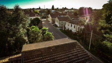 A calm residential street with trees and old houses, showing a peaceful suburban environment in the late afternoon sun. clipart