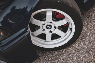 Villamarzana, İtalya 17 Eylül 2024: Performans lastikli bir BMW tekerleğinin yakın çekimi, spor kırmızı fren kalibresini gösteriyor.