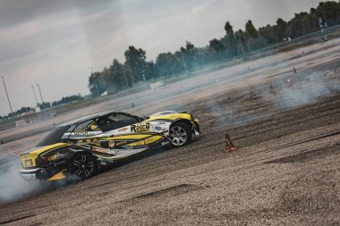 Villamarzana, Italy 17 September 2024: A black drift car powers through a turn, leaving behind a thick trail of tire smoke. clipart