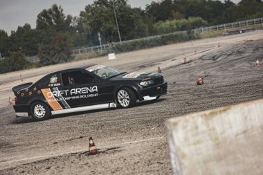 Villamarzana, Italy 17 September 2024: A black drift car powers through a turn, leaving behind a thick trail of tire smoke. clipart