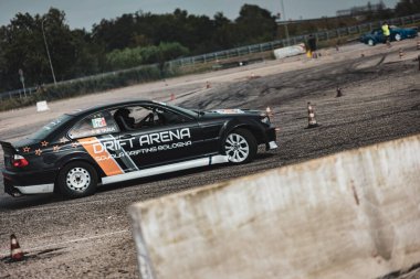 Villamarzana, Italy 17 September 2024: A black drift car powers through a turn, leaving behind a thick trail of tire smoke. clipart