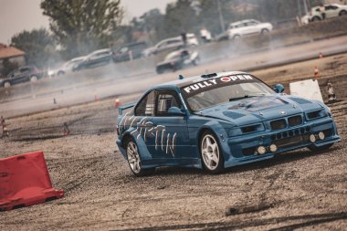 Villamarzana, İtalya 17 Eylül 2024: Kabile tarzı grafiklere sahip siyah drift araba bir olay sırasında sürükleniyor, tampon ayrılırken konilerden kaçınıyor.