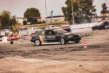 Villamarzana, Italy 17 September 2024: Black drift car from Drift Arena school navigating through a drift zone with cones marking the course during the competition. clipart