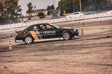 Villamarzana, Italy 17 September 2024: Black drift car from Drift Arena school navigating through a drift zone with cones marking the course during the competition. clipart